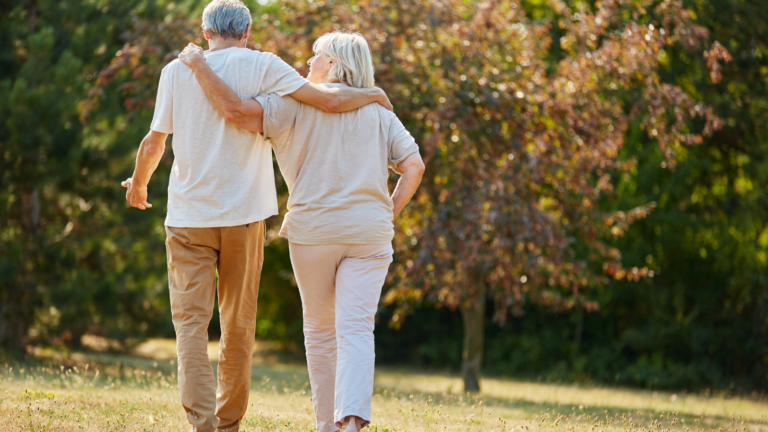 senior couple walking arm in arm through a park