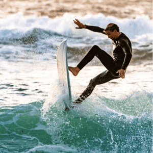 surfer in wetsuit on his toes while surf board is vertical